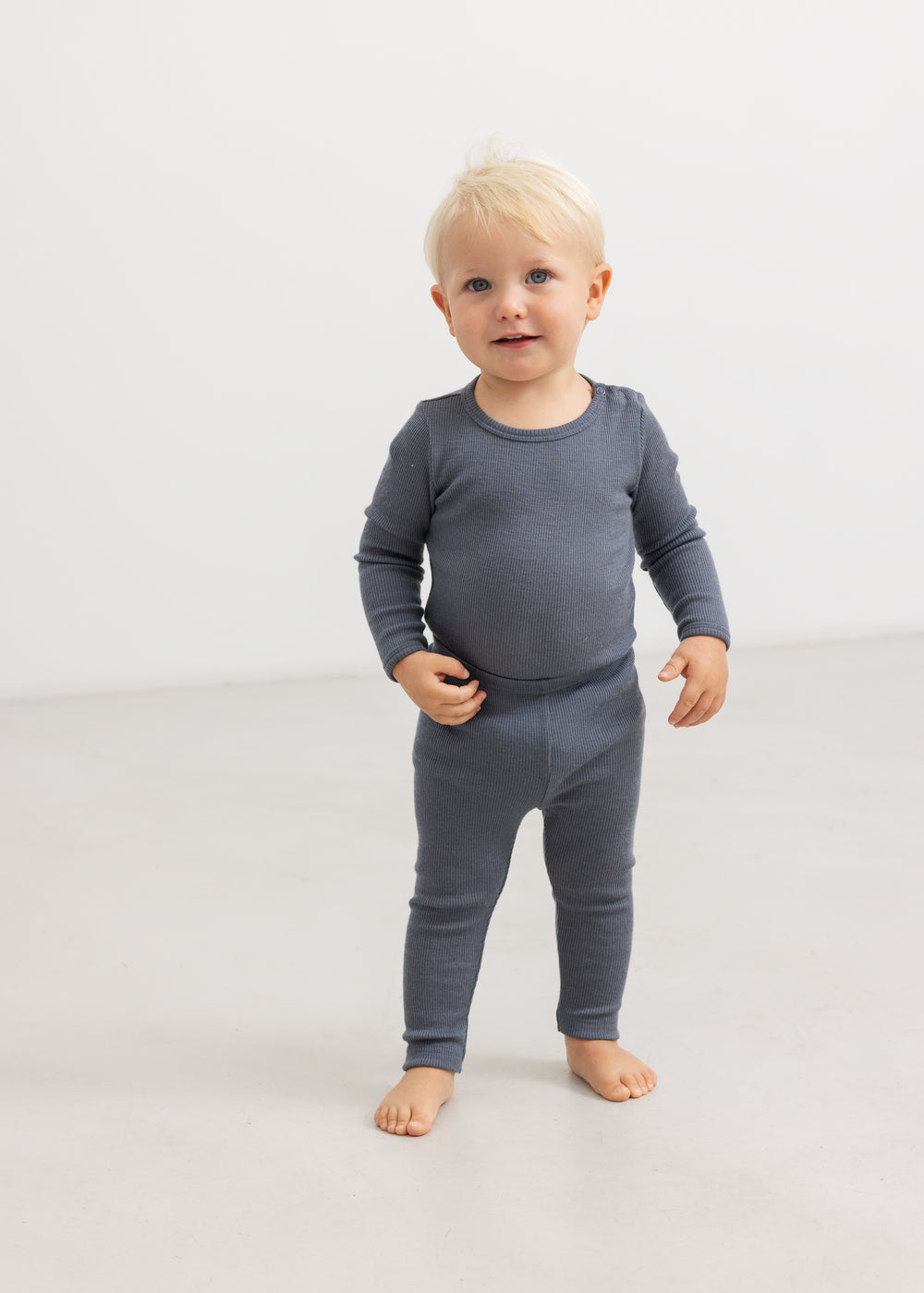 Grå bodystocking med lange ærmer og ben, båret af lille barn