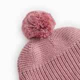 Strikhue i rosa-lilla med stor pompon og ensartet strikmønster