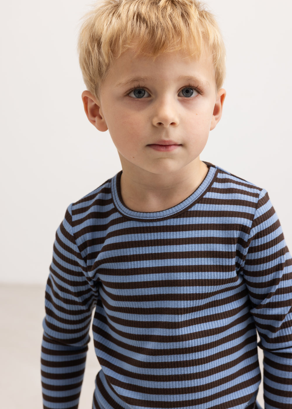 Barn i langærmet t-shirt med blå og mørke striber og rund hals