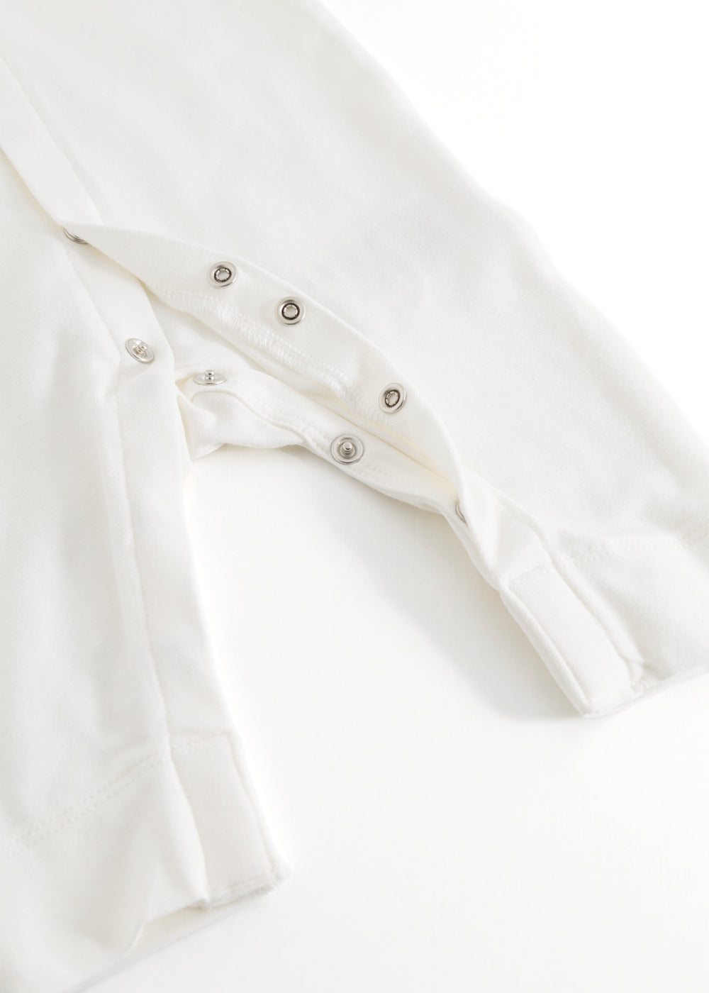 Ricci heldragt i lys off-white med trykknaplukning og picotkant ved front