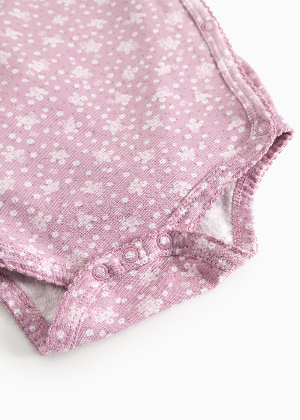 Lyserød bodystocking med blomsterprint, flæsekant og trykknapper i skridtet