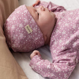 Baby iført lyserød hue med små hvide blomster og matchende heldragt