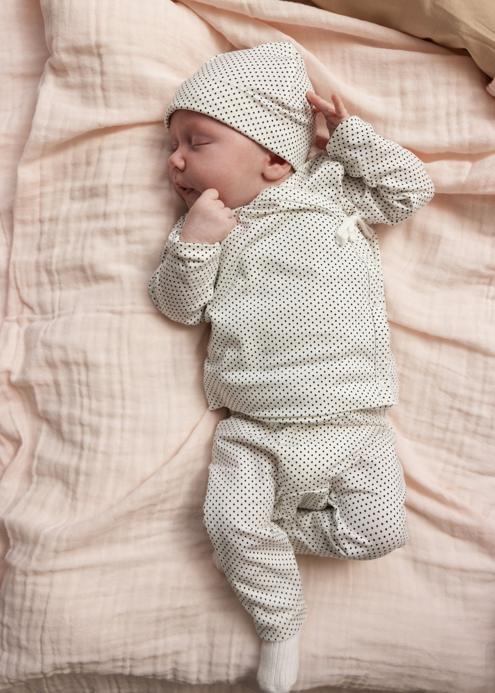 Gråt prikmønstret babysæt med hue og lange ben, baby ligger på sengetøj