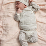 Hvid bluse med små sorte prikker, lange ærmer og bindesnor, på baby