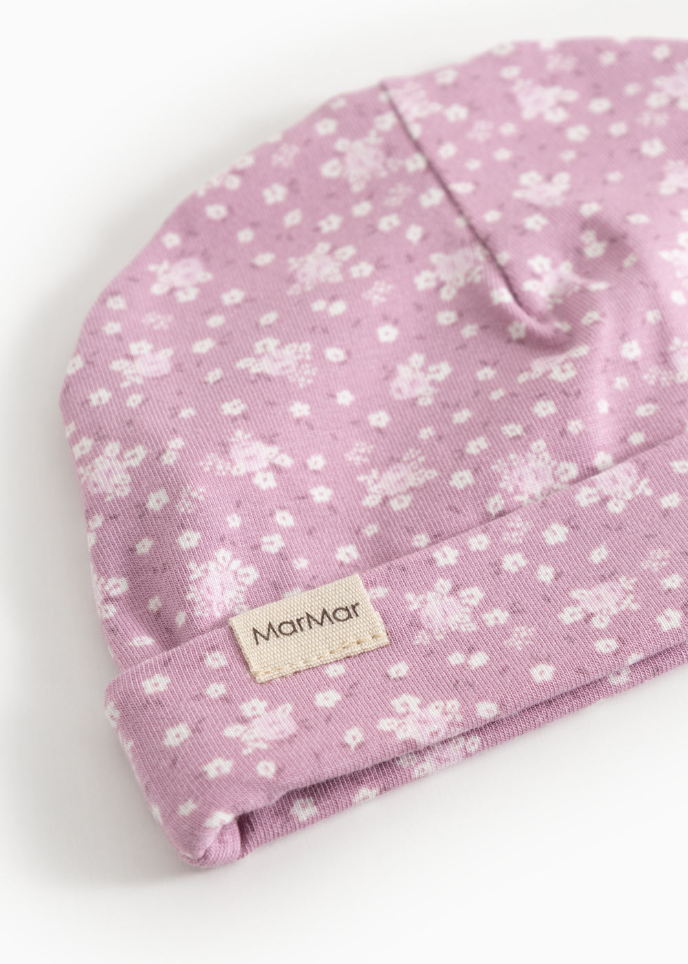 Lyserød babysommercaps/hue med små hvide blomster og mærkelap på opsmøget