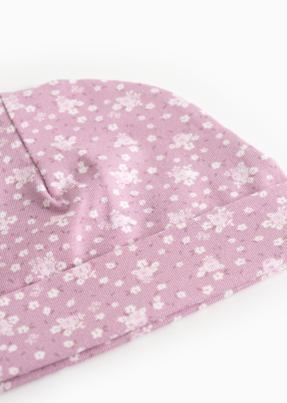 Lyserød babysommercaps/hue med små hvide blomster og sømdetalje i toppen