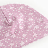 Lyserød babysommercaps/hue med små hvide blomster og sømdetalje i toppen