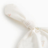 Hvid babyhue med knude og fin ribkant, detalje af stof og mønstre.