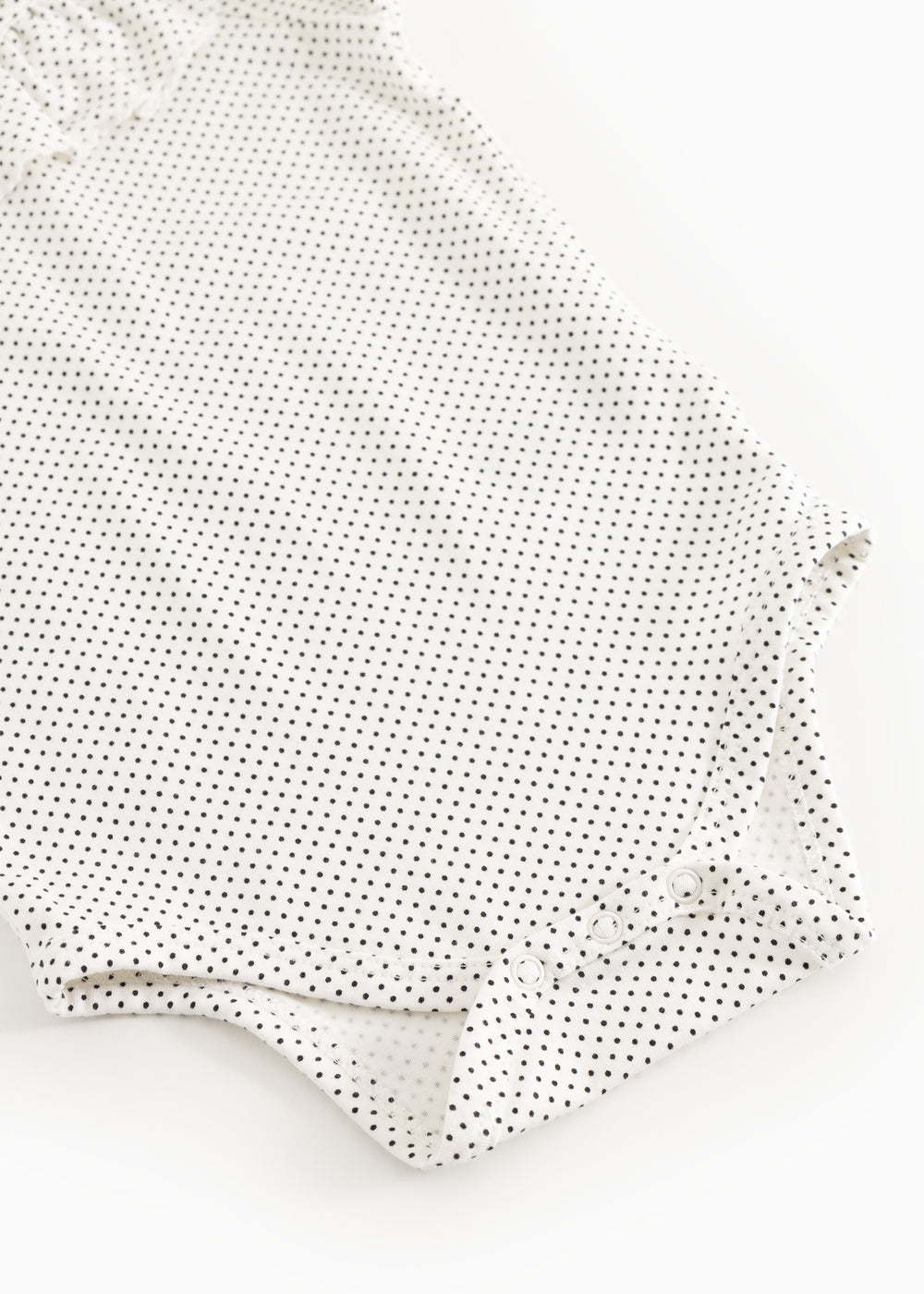 Baby-bodystocking med små sorte prikker, lange ærmer og knapper ved ben