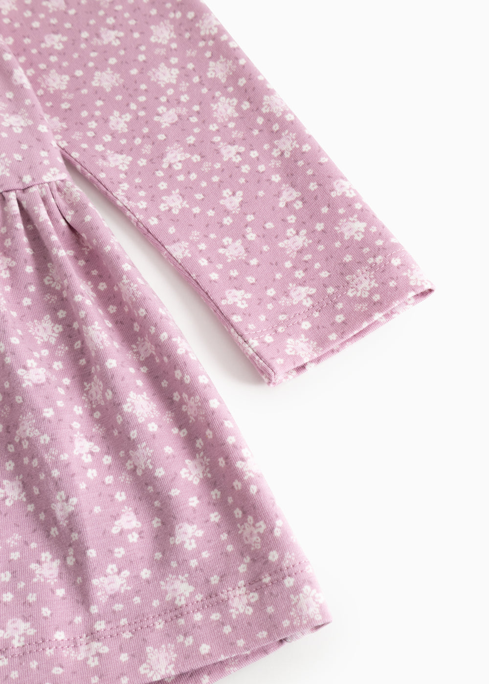 Lilla/pink kjole med små hvide blomster, lange ærmer og rynket skørt