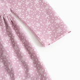 Lilla/pink kjole med små hvide blomster, lange ærmer og rynket skørt