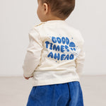 Langærmet bluse i creme med blåt “Good Times Ahead” print på ryggen.