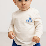 Langærmet bluse i creme med blåt “Hello” print på brystet.