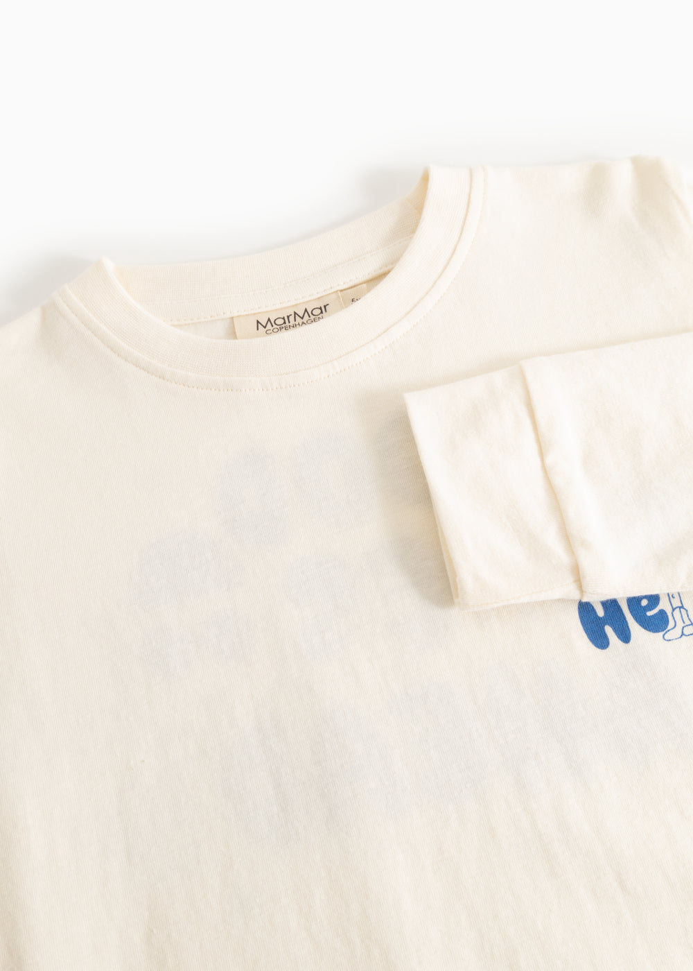 Langærmet bluse i creme med rund hals og blå “Hello” print i højre side.