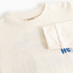 Langærmet bluse i creme med rund hals og blå “Hello” print i højre side.