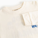 Langærmet bluse i creme med rund hals og blå “Hello” print i højre side.