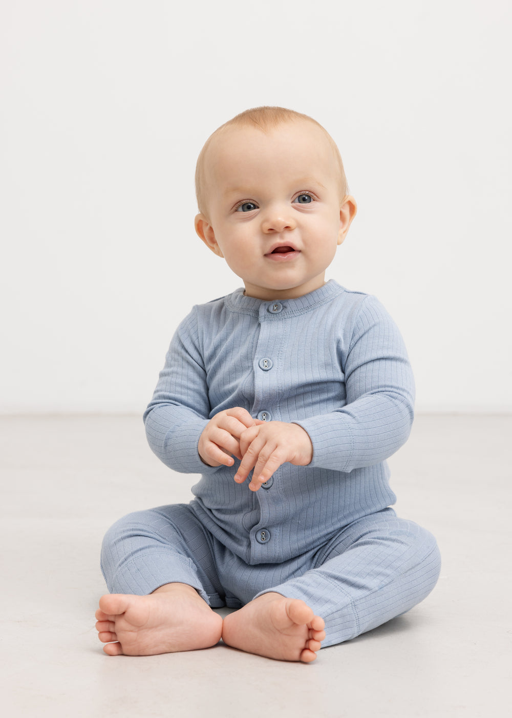 Lyseblå heldragt med knaplukning, båret af baby i helfigur