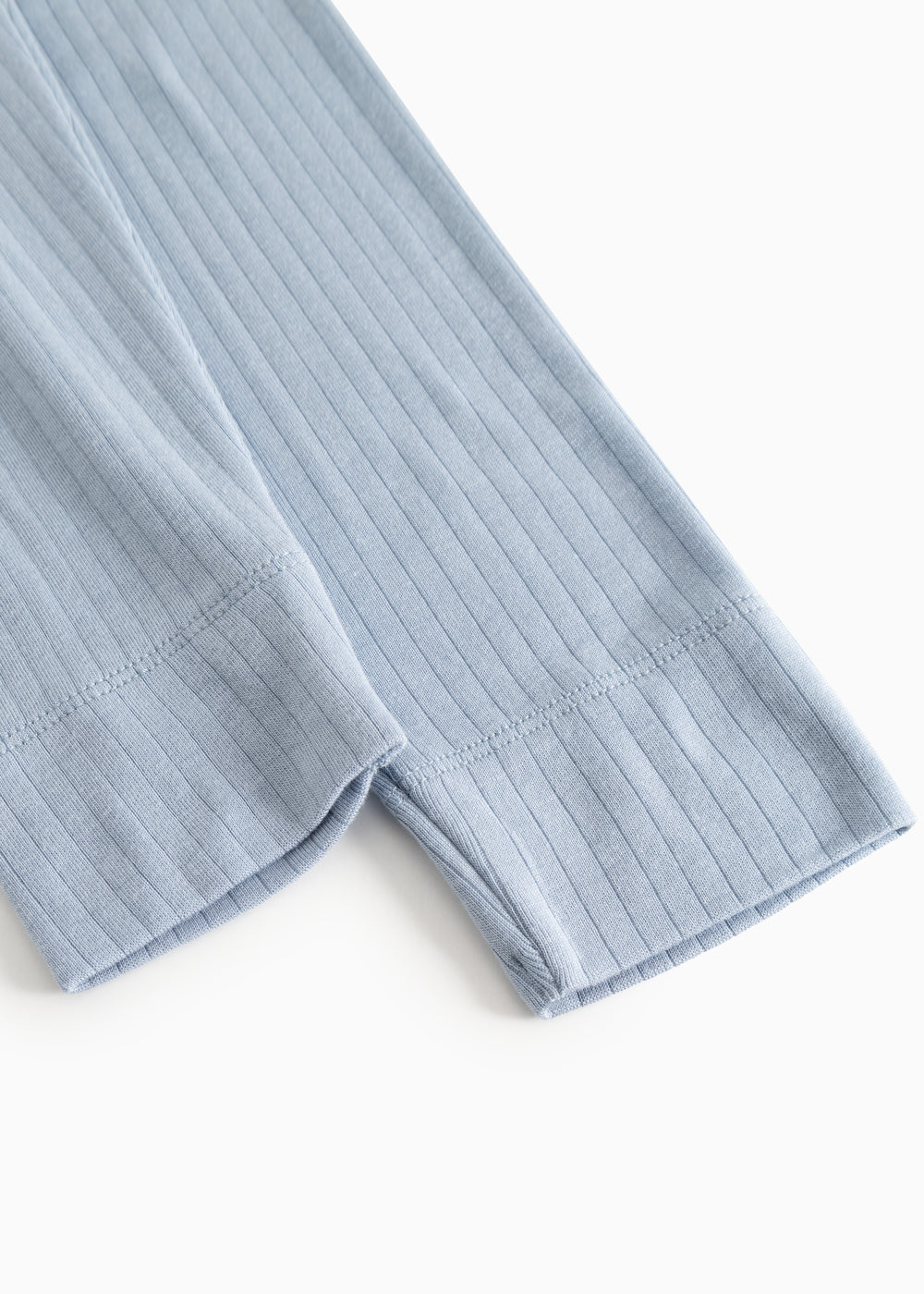 Lyseblå lange leggings i ribbet tekstur, synlig elastik ved benåbningen.