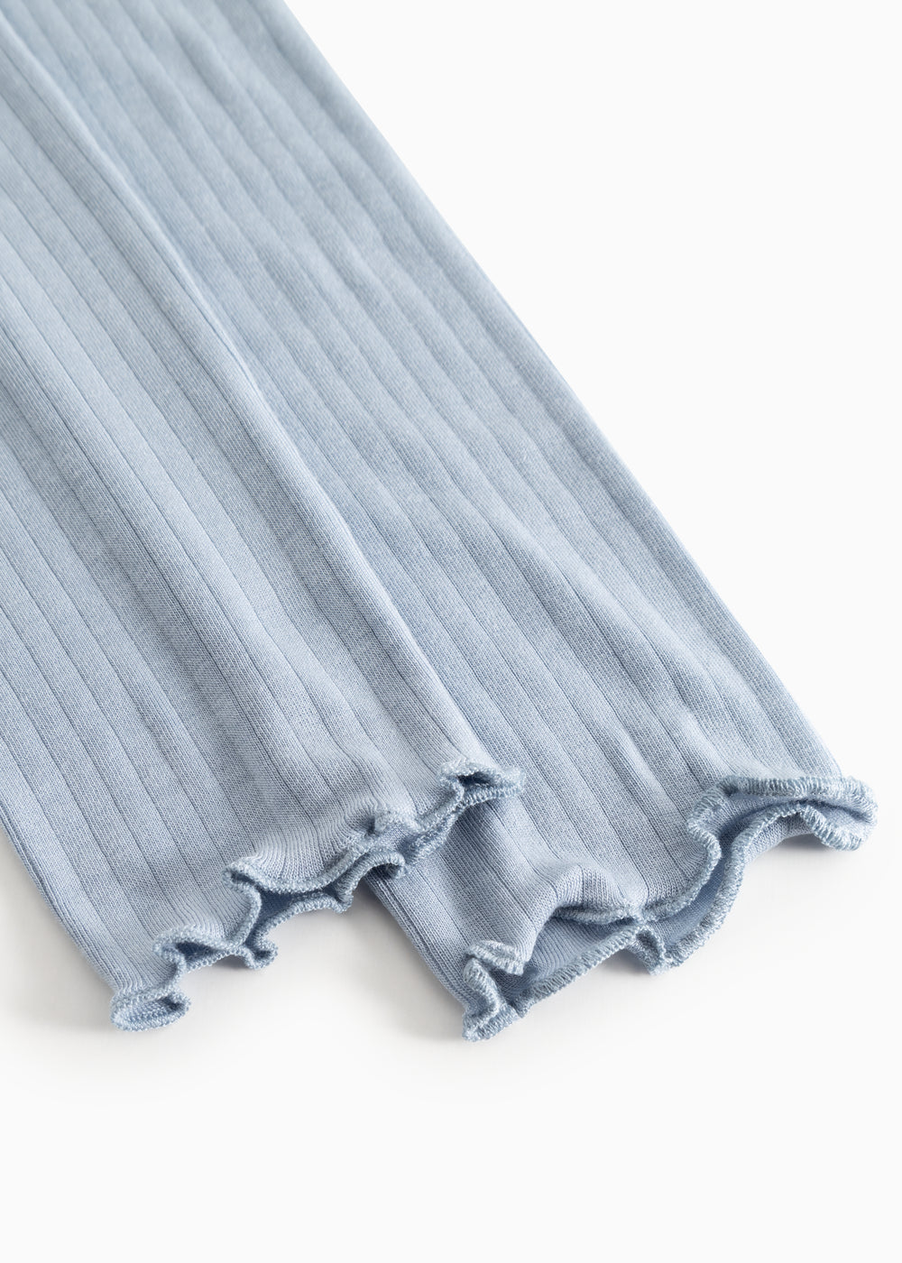 Lyseblå leggings med ribbet kant og frynset benafslutning.