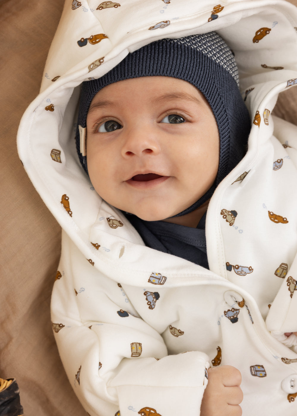 Blå strikhue på baby med mørk bindesnor og mønstret strik.