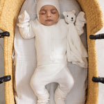 Hvid babydragt i vugge; luffer er ikke synlige i dette udsnit