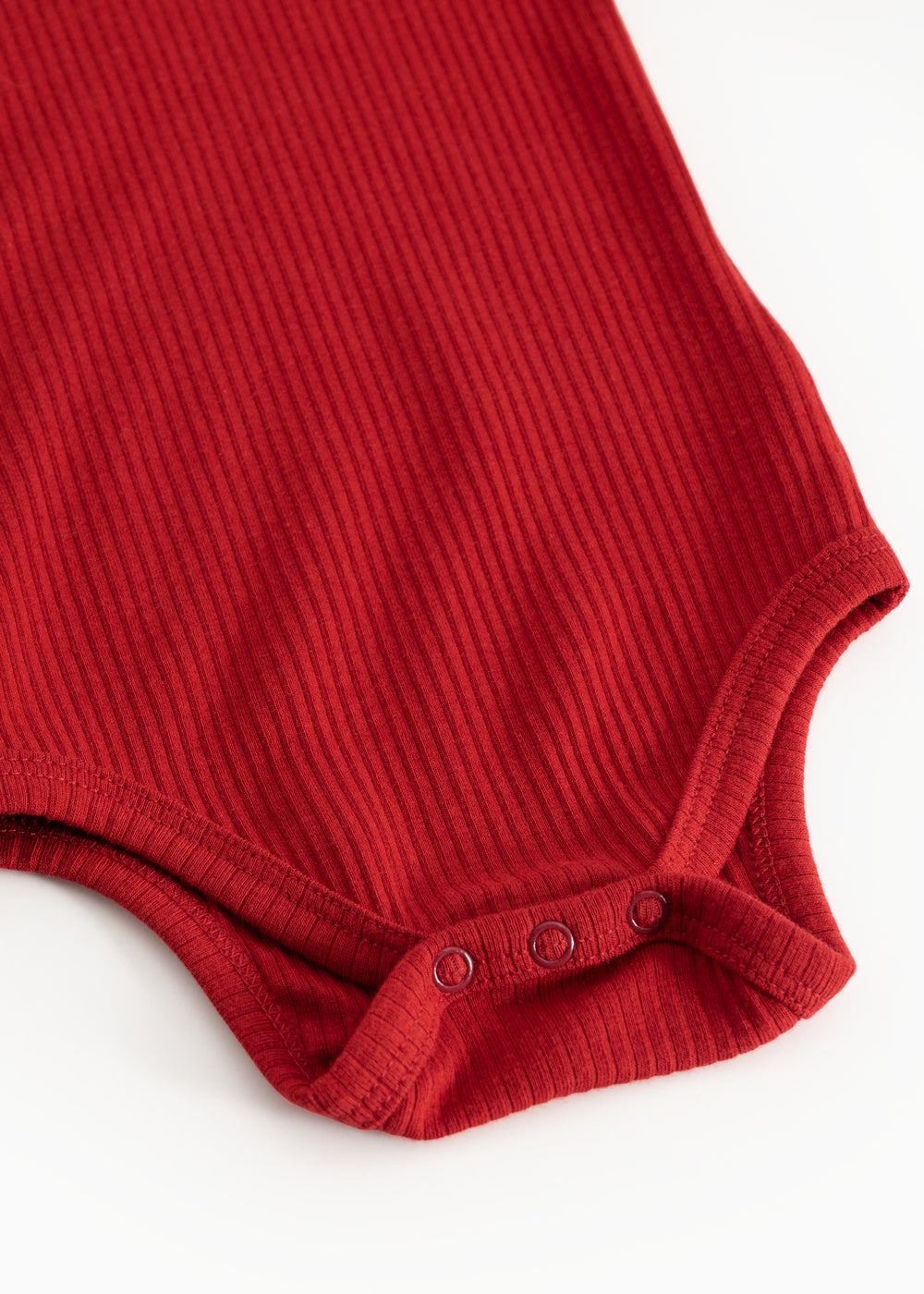 Kirsebærrød bodystocking med ribmønster og trykknapper ved skridtet.
