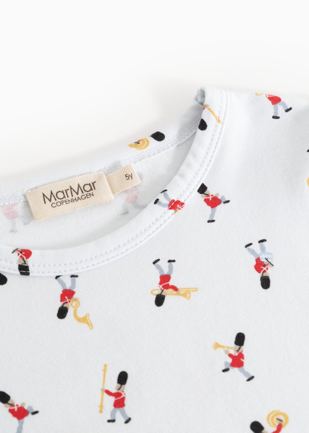 Detalje af hvid pyjamas med musikerprint ved halsudskæring og mærketap