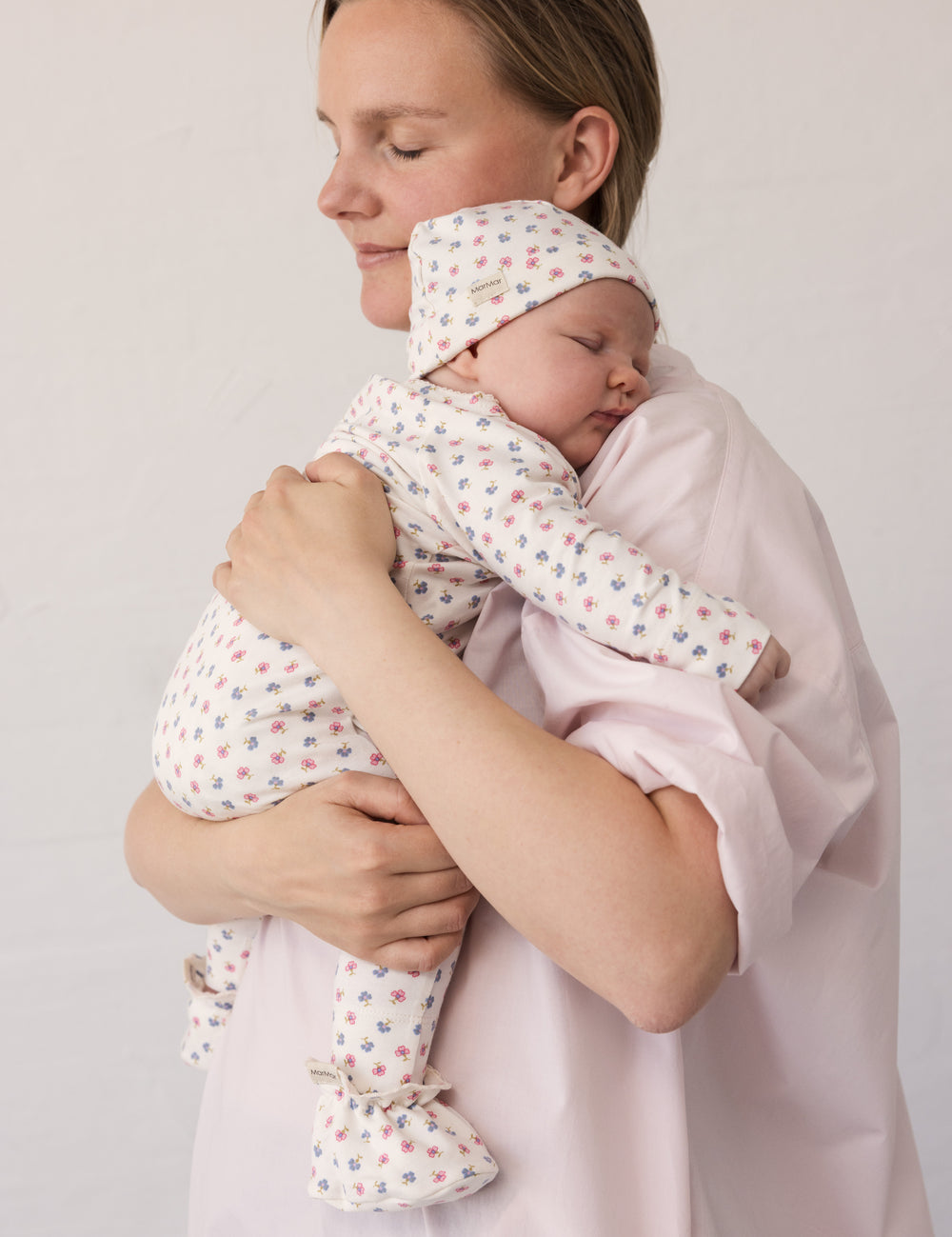 Kvinde iført lyserød kjole mens baby holdes i favn