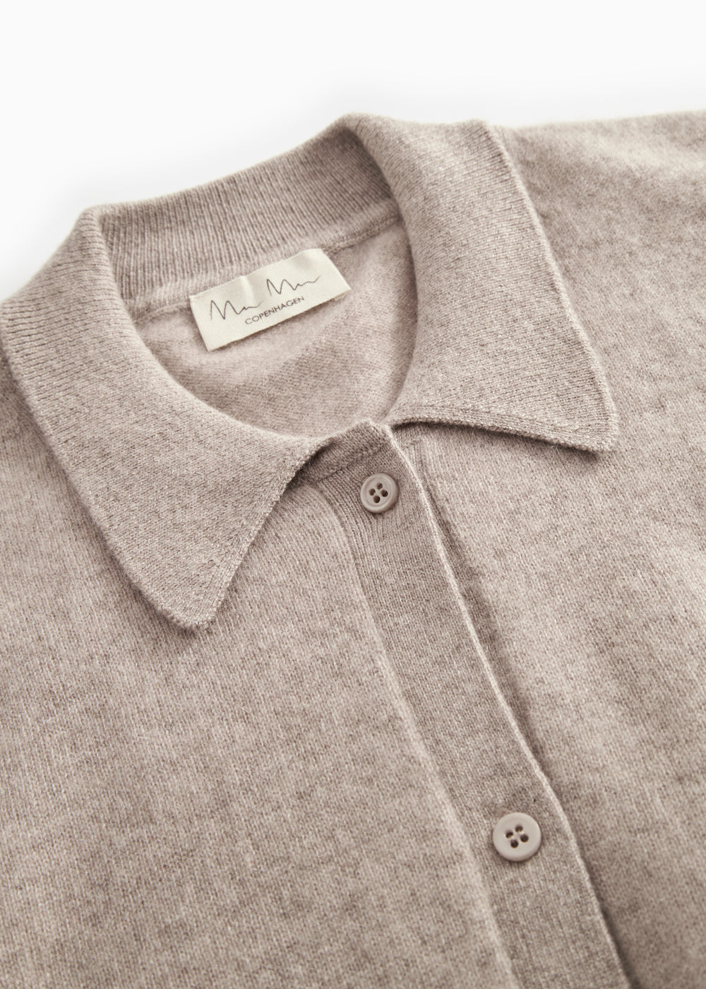 Detalje af gråmeleret cardigan: krave, knapper og indvendigt mærke