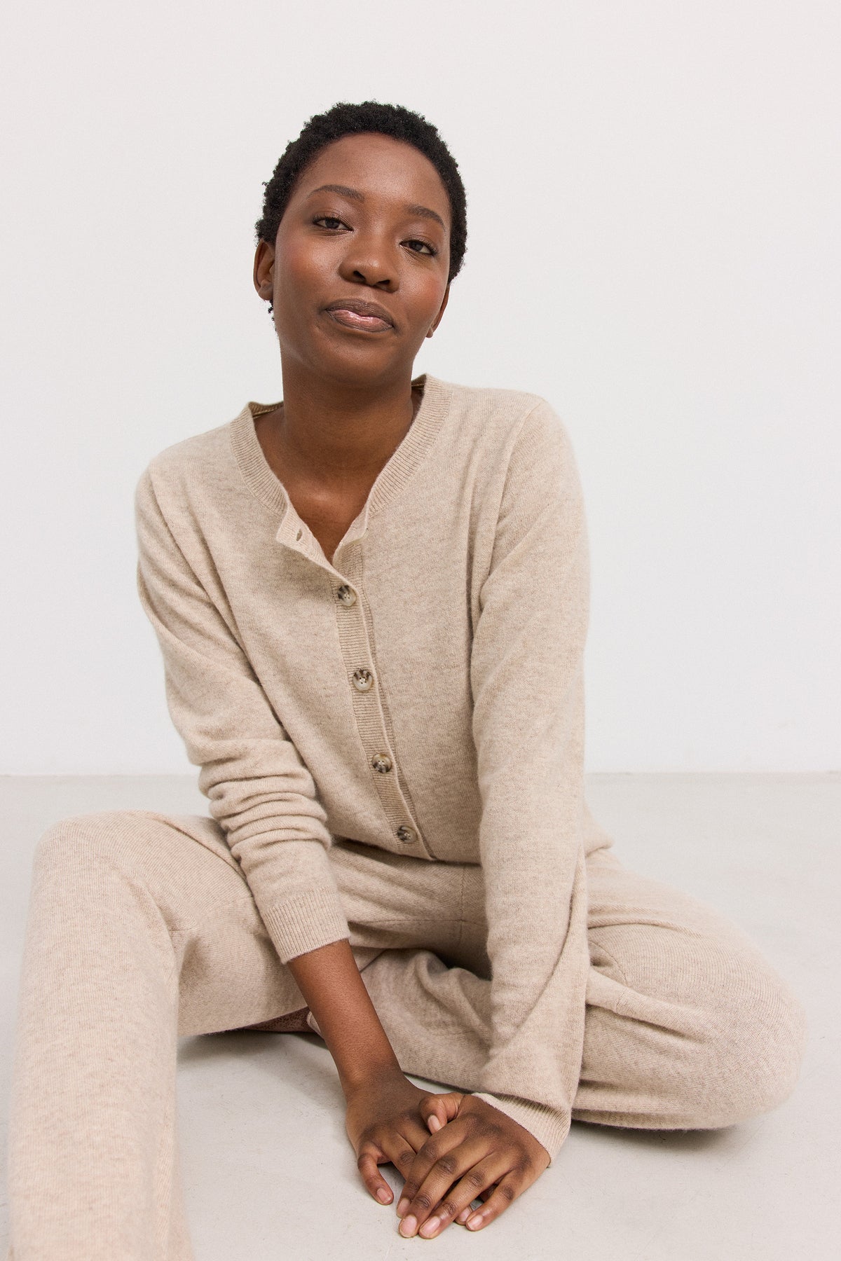 Kvinde i beigefarvet strikcardigan og matchende bukser