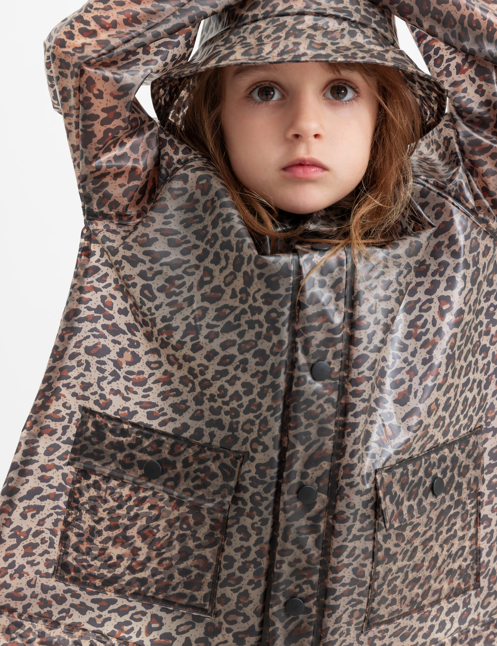 Barn iført leopardmønstret regnfrakke og regnhat.