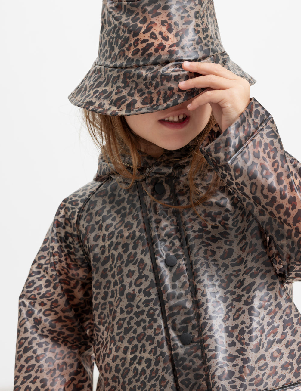 Barn iført leopardmønstret regnfrakke og regnhat.