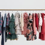 Festtøj og julekjoler til børn hængende på tøjstativ i forskellige farver