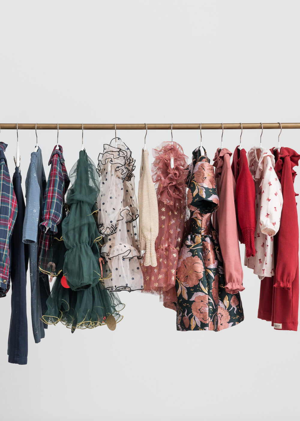 Festtøj og julekjoler til børn hængende på tøjstativ i forskellige farver