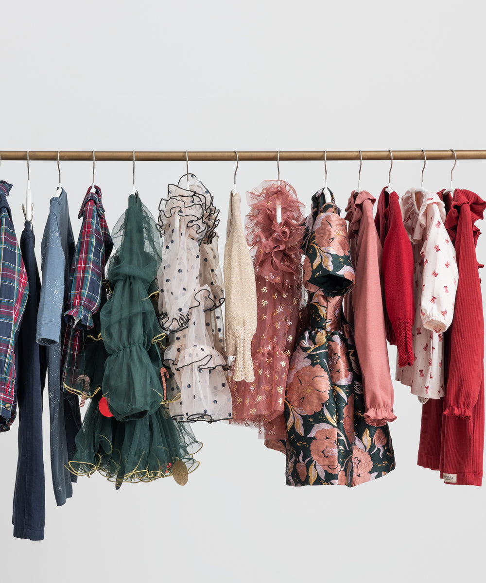 Festtøj og julekjoler til børn i forskellige farver hængende på tøjstativ 