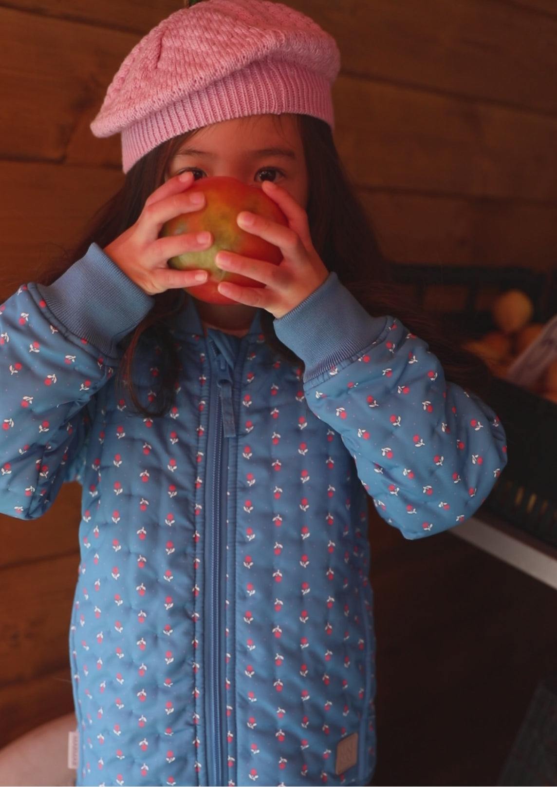 Barn i blå termo jakke med blomstret print og lyserød strikket hue 