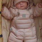 Baby sover i lyserød dundragt med hue