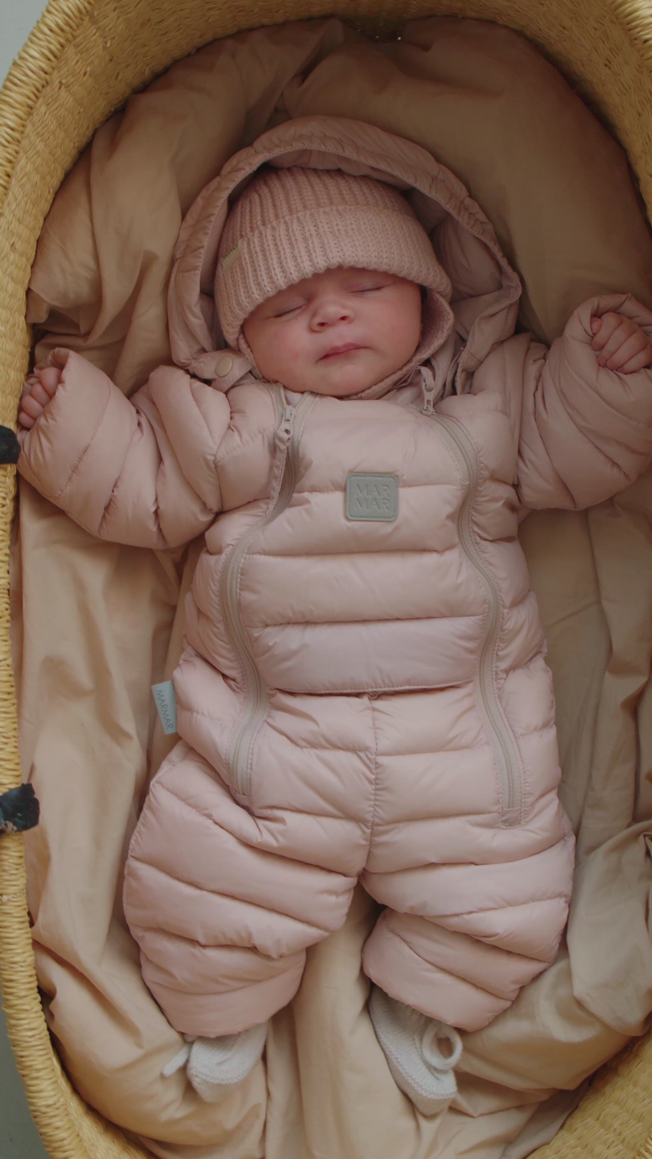 Baby sover i lyserød dundragt med hue