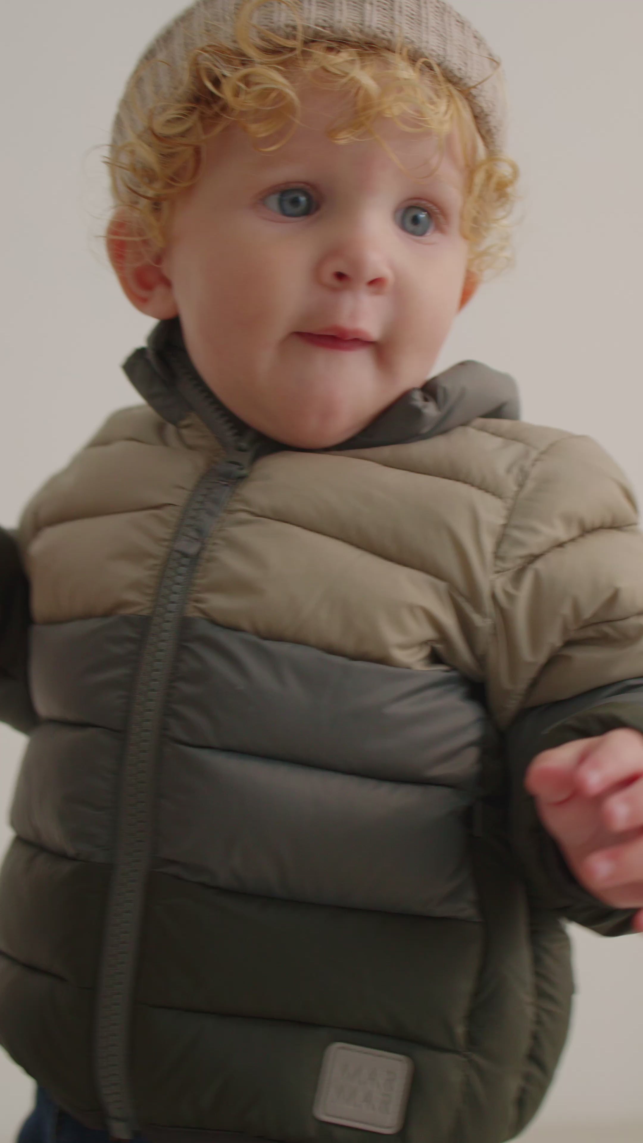 Barn iført vatteret jakke i beige og grønne nuancer